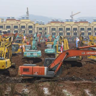 Le ballet des pelles mécaniques pour construire un nouvel hôpital à Wuhan. [Keystone - Chinatopix via AP]