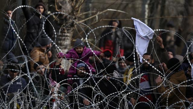 Des migrants se tiennent derrière du fil de fer barbelé près de Kastanies, à la frontière gréco-turque, le 2 mars 2020. [Keystone/ap photo - Giannis Papanikos]