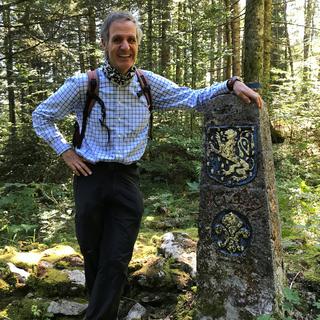 Olivier Cavaleri, historien, ingénieur et auteur des guides "Histoire de bornes" (éd. Slatkine) à côté de la borne 103 dans la forêt du Risoud (ou Risoux). [RTS - Yves-Alain Cornu]