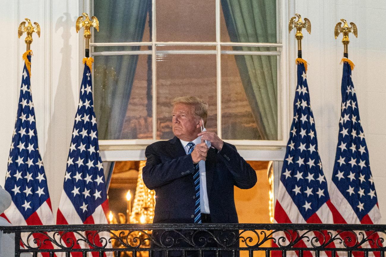 Donald Trump enlève son masque après son retour à la Maison Blanche, après avoir passé quelques jours à l'hôpital militaire Walter Reed. Washington DC, le 5 octobre 2020. [Keystone/epa - Ken Cedeno/Pool]