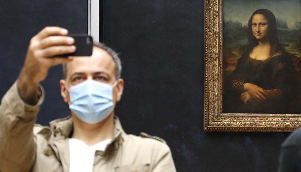 L'inamovible Mona Lisa s'amuse désormais des visiteurs masqués lui tirant le portrait au Louvre. Paris, le 6 juillet 2020. [AFP - François Guillot]
