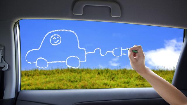 Un enfant dessine une voiture électrique sur la fenêtre d'une voiture. [Depositphotos - tomwang]