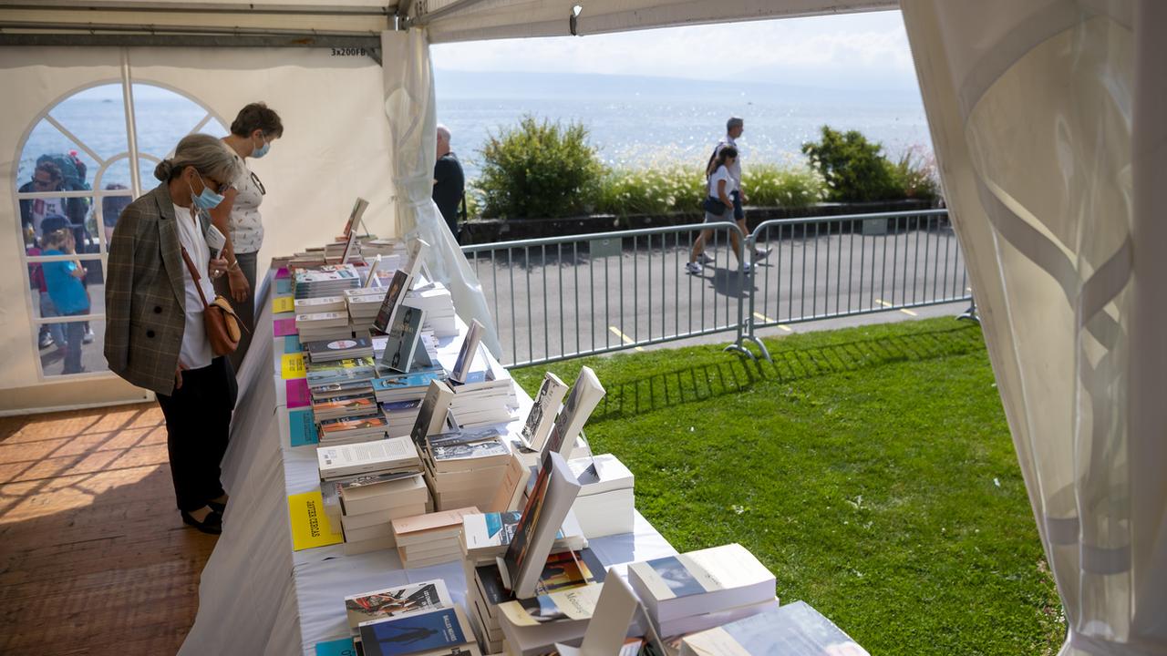 Des personnes regardent des livres sous une tente lors de la 12eme édition du "Livre sur les quais", le 4 septembre 2021. [Keystone - Jean-Christophe Bott]