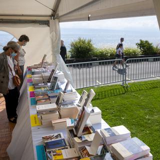 Des personnes regardent des livres sous une tente lors de la 12eme édition du "Livre sur les quais", le 4 septembre 2021. [Keystone - Jean-Christophe Bott]