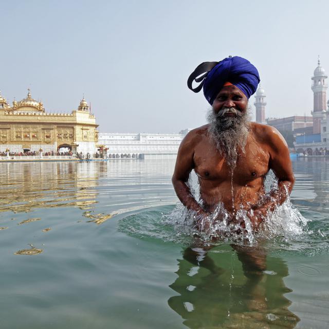 Un dévot sikh se baigne dans l'étang sacré du Temple d'Or, le plus saint des lieux sikhs (vu dans le brouillard en arrière-plan), à l'occasion de l'anniversaire de naissance du dixième gourou sikh, Gobind Singh, à Amritsar, en Inde, le 20 janvier 2021. [EPA/Keystone - Raminder Pal Singh]