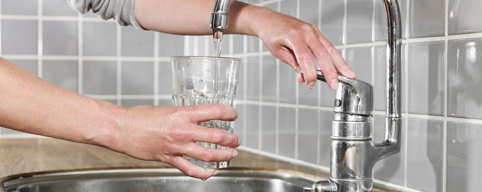 Gros plan sur une main en train de se servir un verre d'eau du robinet. [Depositphotos - YAYImages]