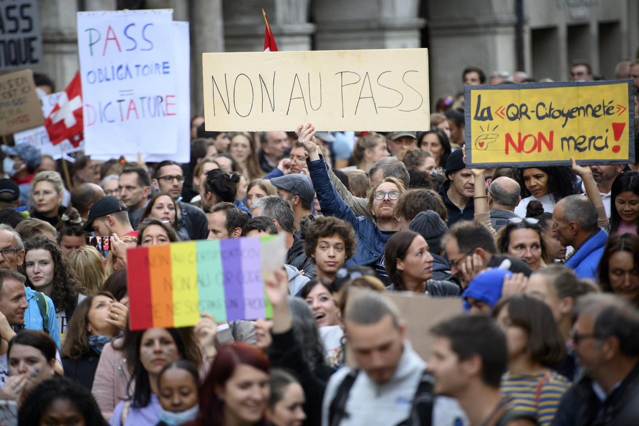 Des personnes brandissent des pancartes sur la place de la Palud lors d'une manifestation contre l'obligation du certificat Covid le mardi 21 septembre 2021 à Lausanne. [Keystone - Laurent Gillieron]