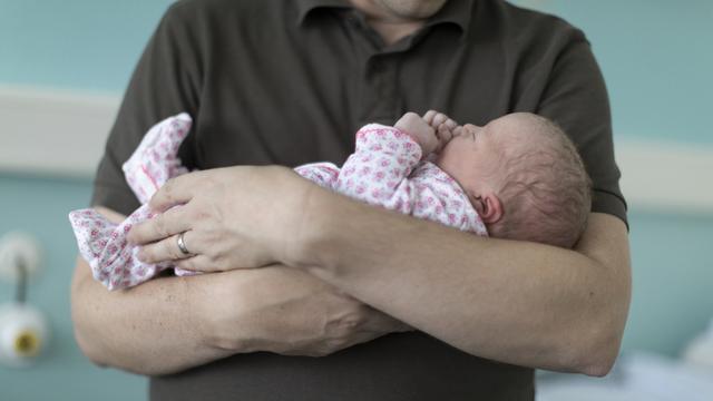 Un père tenant son bébé dans les bras. [KEYSTONE - Gaetan Bally]