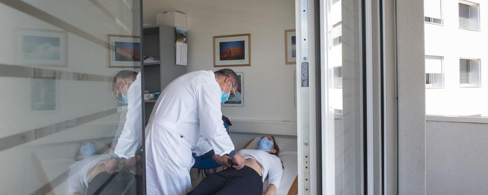 Un médecin examine une patiente atteinte du Covid dans un hôpital de Lugano. [Keystone - Ti-Press/Alessandro Crinari]