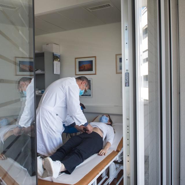 Un médecin examine une patiente atteinte du Covid dans un hôpital de Lugano. [Keystone - Ti-Press/Alessandro Crinari]