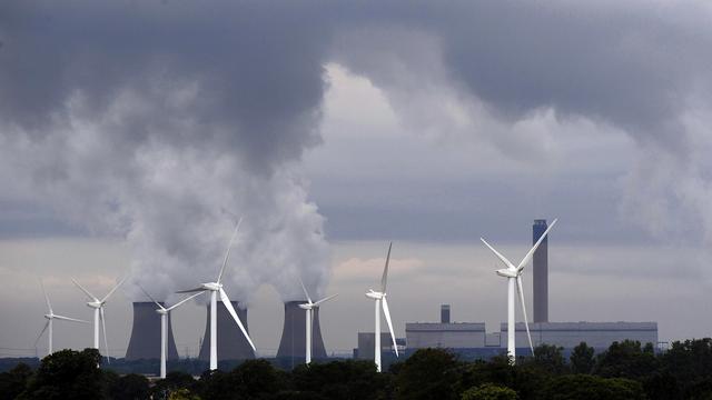 Une centrale à charbon côtoie une rangée d'éoliennes, à Drax en Angleterre. [AP/Keystone - John Giles]