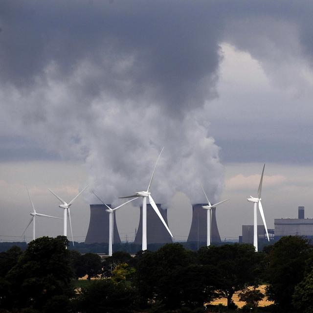 Une centrale à charbon côtoie une rangée d'éoliennes, à Drax en Angleterre. [AP/Keystone - John Giles]