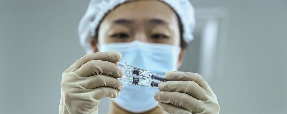 Un membre du personnel soignant tient dans ses mains des seringues contenant le vaccin anti-Covid du laboratoire Sinopharm, le 25 décembre 2020. [AP/Keystone - Zhang Yuwei]