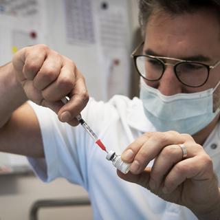 Un infirmier prépare les premières doses du vaccin Pfizer-BioNTech contre le Sars-Cov-2 dans un EMS dans le canton de Vaud le 30 decembre 2020. [Keystone - Jean-Christophe Bott]