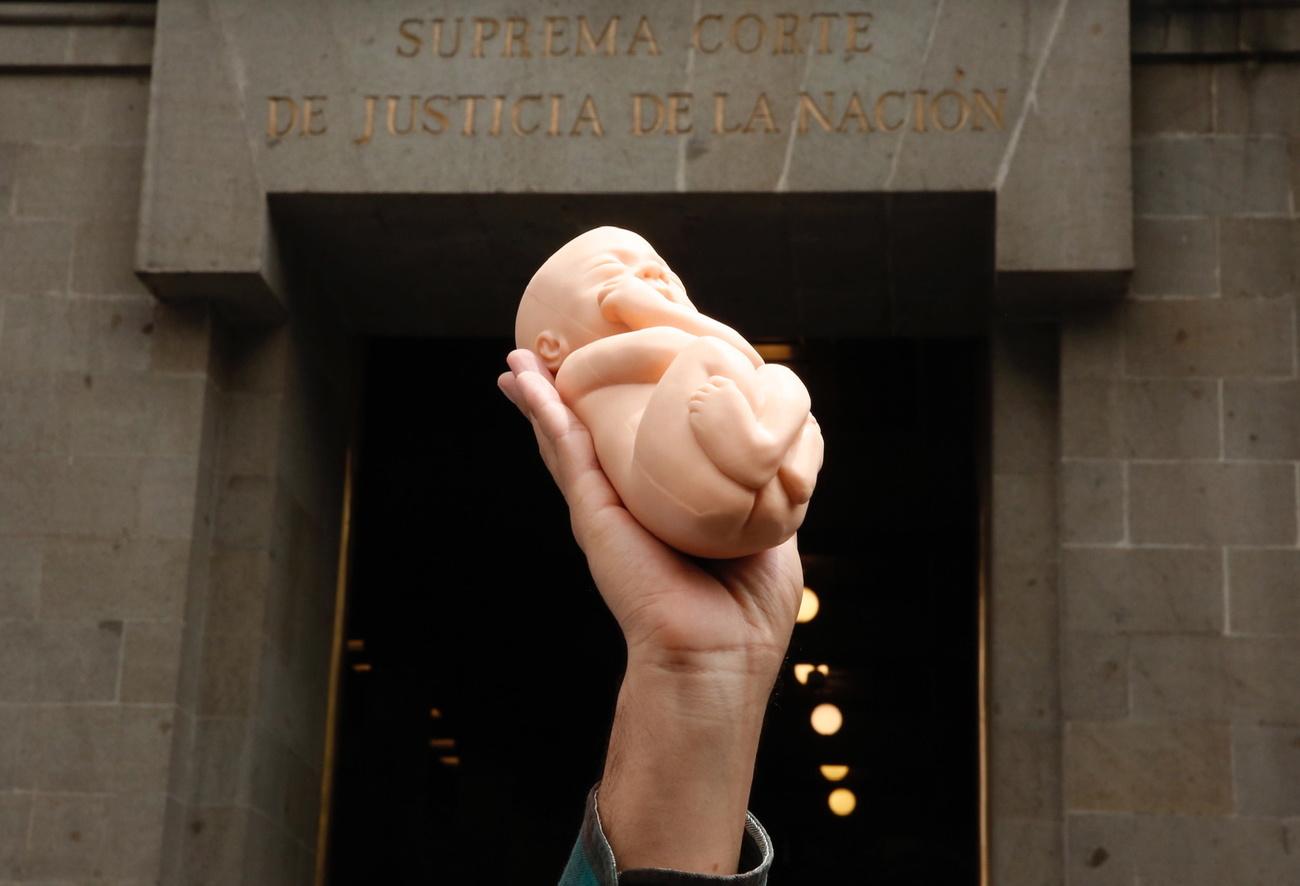 Une personne brandit un bébé en plastique durant une manifestation anti-avortement devant la Cour Suprême du Mexique. Mexico City, le 7 septembre 2021. [Keystone - Carlos Ramirez]