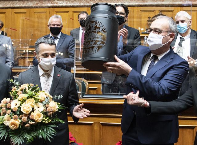 Le nouveau président de la Confédération, Guy Parmelin (droite), reçoit un bidon de lait aux côtés du vice-président de la Confédération, Ignazio Cassis (gauche), lors de la session d'hiver des Chambres fédérales. Berne, le 9 décembre 2020. [Keystone - Peter Schneider]