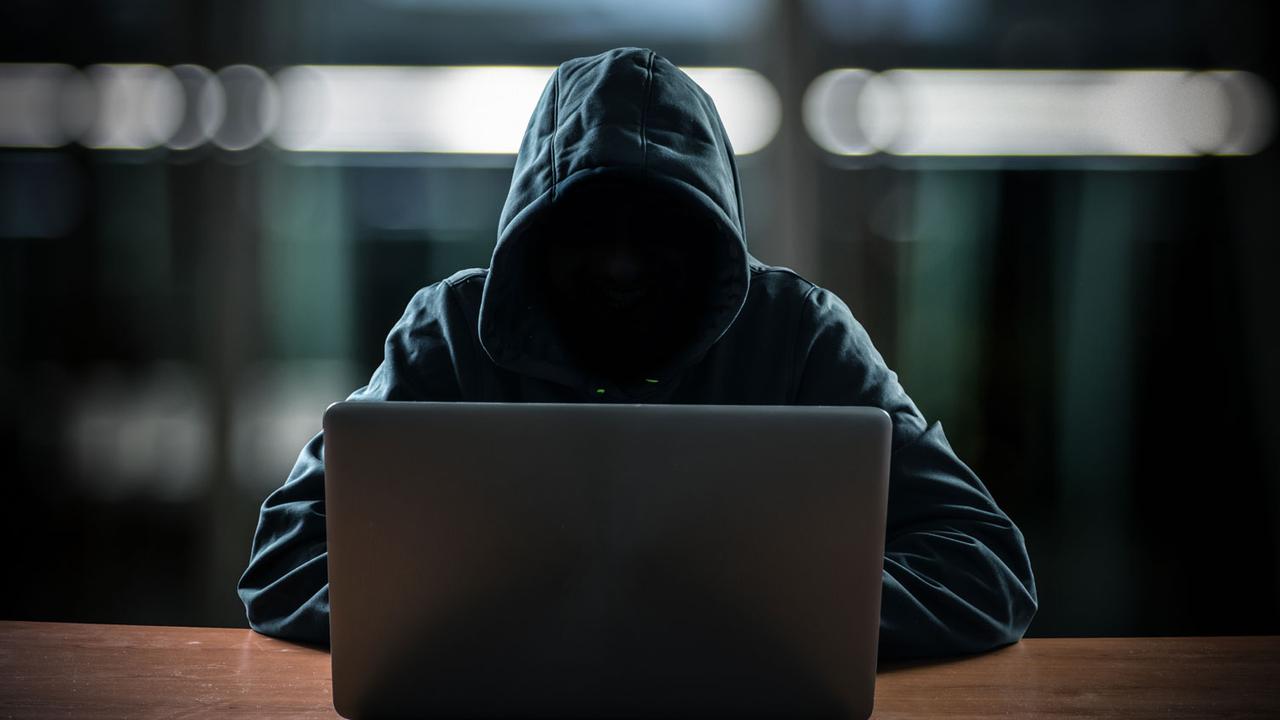 Un hacker se tient derrière son écran d'ordinateur. [Depositphotos - minervastock]