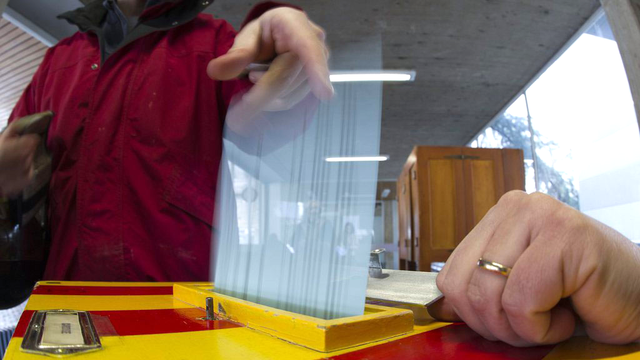 Une citoyenne met son bulletin de vote dans l'urne à Carouge (GE), lors des votations fédérales et cantonales du 11 mars 2012. [Keystone - Salvatore Di Nolfi]