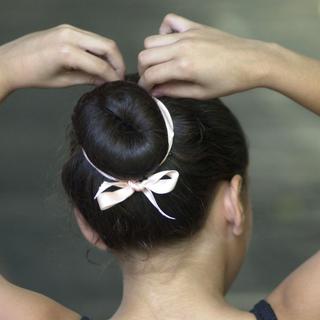 Une jeune ballerine retouche sa coiffure (image d'illustration). [Keystone/AP Photo - Leslie Mazoch]