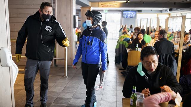 Une agente de police discute avec un tenancier de restaurant sur le domaine skiable de Villars-sur-Ollon (VD) le 19 décembre 2020. [Keystone - Valentin Flauraud]