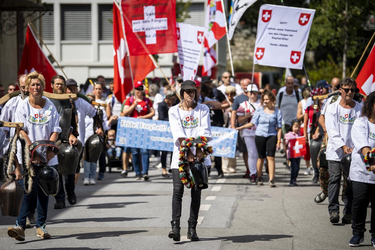 Des personnes, et notamment des "Freiheitstrychler", défilent contre les mesures sanitaires le 28 août 2021 à Brigue. [Keystone - Jean-Christophe Bott]