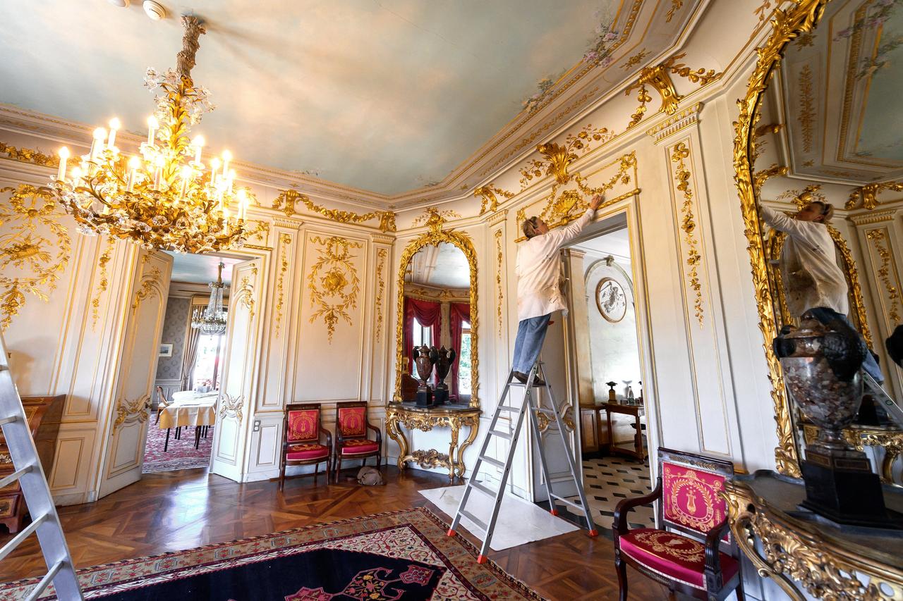 Un peintre fait des retouches sur les dorures de la villa La Grange. [AFP - Fabrice Coffrini]