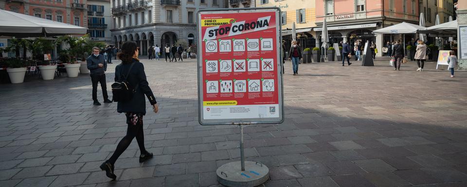 Une affiche indique l'entrée en vigueur du port obligatoire de masques dans les lieux publics fréquentés de la ville de Lugano, le samedi 27 mars 2021. [Keystone - Ti-Press/Elia Bianchi]