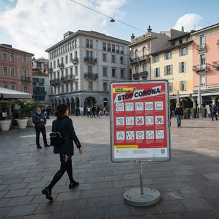 Une affiche indique l'entrée en vigueur du port obligatoire de masques dans les lieux publics fréquentés de la ville de Lugano, le samedi 27 mars 2021. [Keystone - Ti-Press/Elia Bianchi]