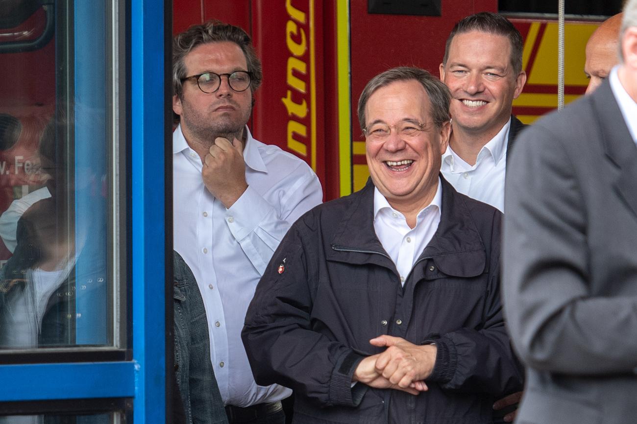 Armin Laschet (au centre), candidat favori à la succession de la chancelière allemande Angela Merkel, lors de son fou rire dans la ville de Erftstadt (ouest), particulièrement dévastée par les inondations. [Keystone - DPA/Marius Becker]