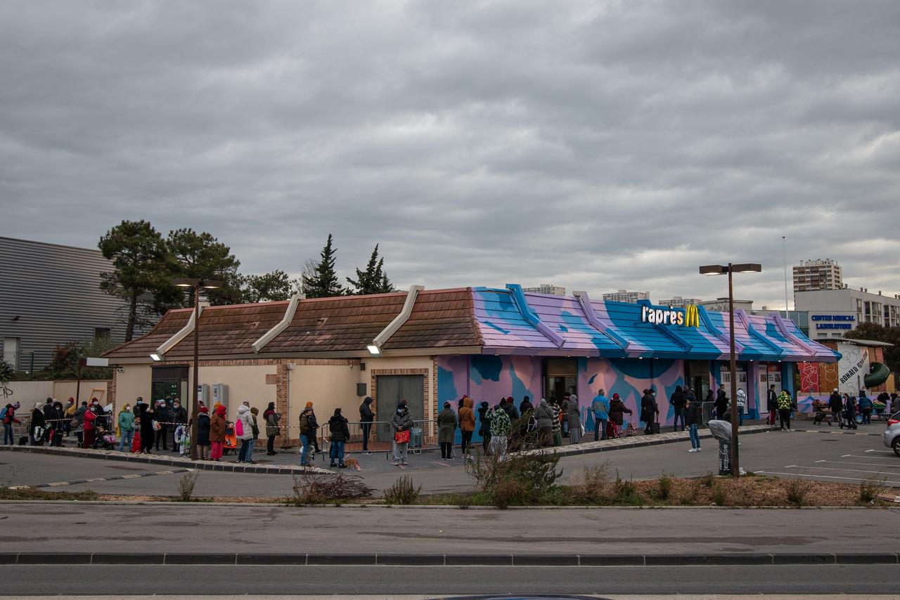 Des dizaines de personnes font la queue devant l'Après M. pour obtenir un colis alimentaire. [RTS - Charles Bury]