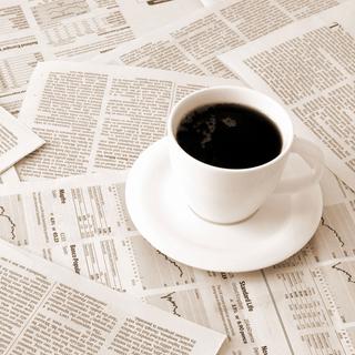 Gros plan sur un café posé sur des journaux. [Depositphotos - Viviamo]