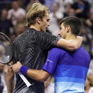 Les joueurs de Tennis Alexander Zverev et Novak Djokovic s'enlacent en fin de match. [AP Photo/ Keystone - John Minchillo]