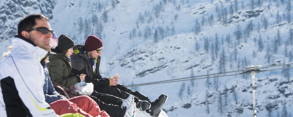 Des skieurs mangent dans la neige à Bosco Gurin. [Keystone/Ti-Press - Alessandro Crinari]