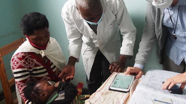 Le Dr. Ludovico Cobuccio montre à un infirmier au Centre de Santé de Bweyeye (Rwanda), comment utiliser l'application développée par le projet DYNAMIC pour examiner une patiente. 
Aicha Yusuf
Unisanté [Unisanté - Aicha Yusuf]