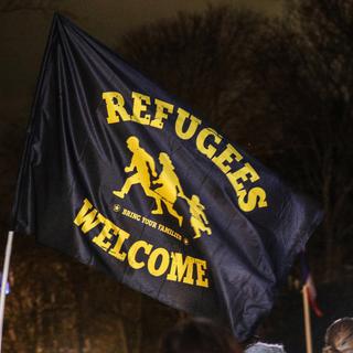 Des personnes manifestent pour rendre hommage aux 27 migrants morts dans le canal de la Manche, en tenant un drapeau avec la phrase "Refugees Welcome" au Parc de Richelieu à Calais, France, le 25 novembre 2021. [EPA/Keystone - Mohammed Badra]