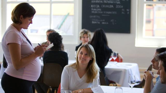 Une femme à un stade de grossesse avancée fait le service dans un restaurant zurichois, le 9 mai 2005. [Keystone - Gaetan Bally]