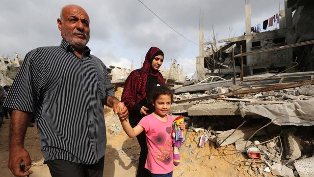 Une famille palestinienne retourne à sa maison en ruine, le matin suivant le cessez-le-feu entre le Hamas et Israël, le 21 mai 2021. [Keystone - Ashraf Amra]