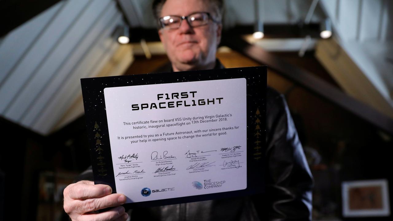 James Clash, un des futurs touristes de l'espace, montre fièrement son ticket pour voyager avec la compagnie Virgin Galactic. [Mike Segar]