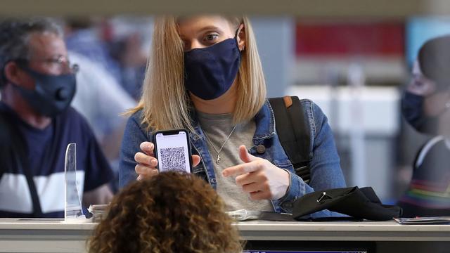 Une femme montre son pass sanitaire à un guichet. [Keystone - Robert Ghement]