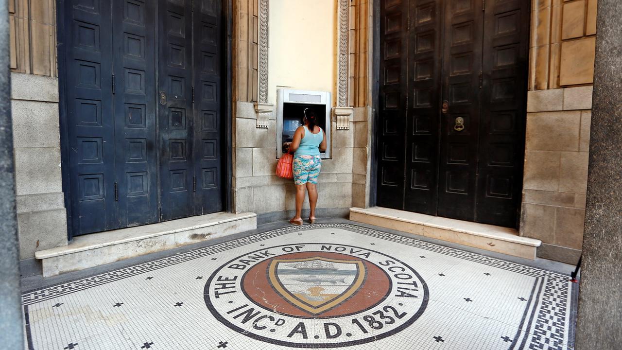 Une femme retire de l'argent dans l'entrée d'une banque de La Havane. Cuba, 1er janvier 2021. [Keystone/epa - Ernesto Mastrascusa]