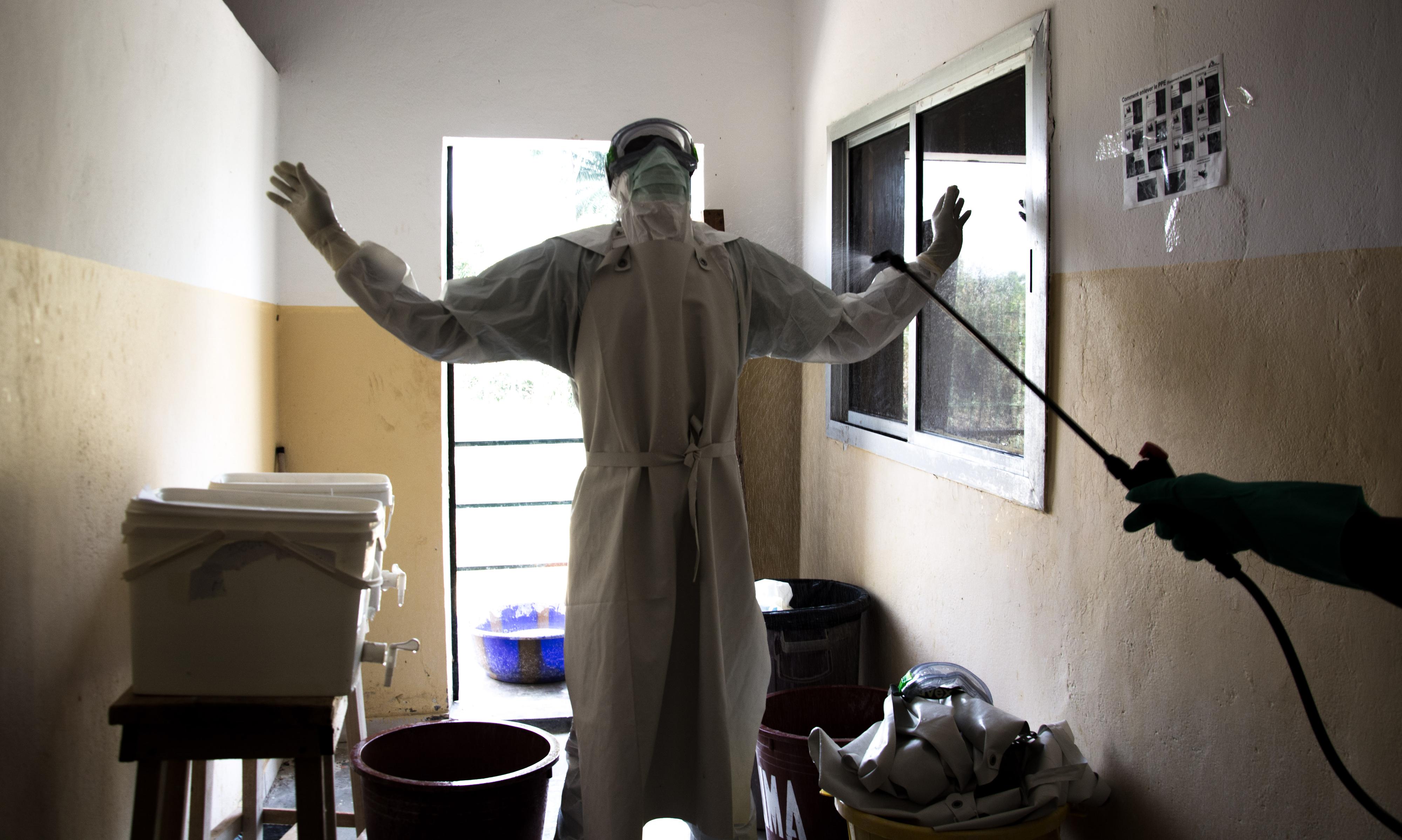 Un soignant de malades Ebolas, en tenue de protection, se fait désinfecter [RTS - Carol Valade]