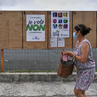 Une femme passe devant des affiches électorales appelant à voter non au référendum à Nouméa, en Nouvelle-Calédonie, dimanche 12 décembre 2021. [AP Photo/Keystone - Clotilde Richalet]