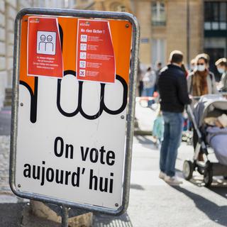 Un panneau indique "On vote aujourd'hui". [Keystone - Jean-Christophe Bott]
