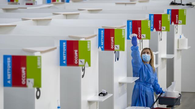 Une personne désinfecte un box dans un centre de vaccination de Genève. [Keystone - Martial Trezzini]