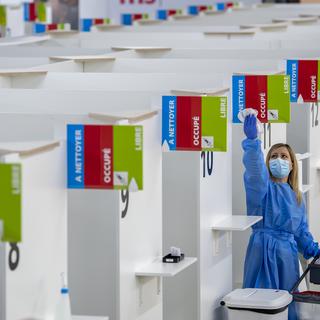 Une personne désinfecte un box dans un centre de vaccination de Genève. [Keystone - Martial Trezzini]