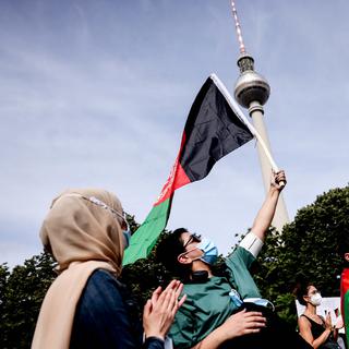 Un manifestant avec un drapeau national afghan à Berlin le 28 août 2021. [Keystone/EPA - Filip Singer]