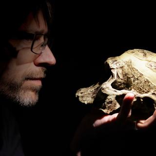 Un homme examine un crâne qu'il tient dans la main. [Depositphotos - IvanM77]