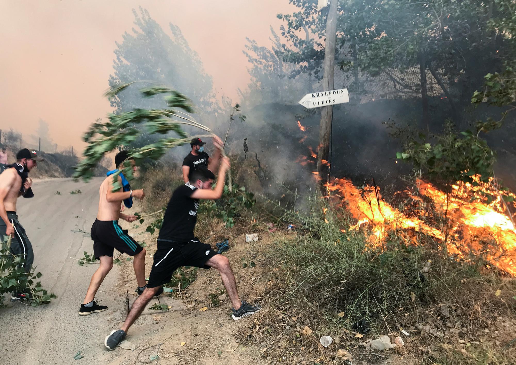 Des personnes tentent d'éteindre un incendie à l'aide de branches dans la province montagneuse de Tizi Ouzou. [Reuters - Abdelaziz Boumzar]