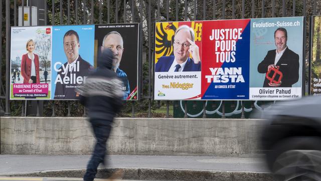 Une personne passe devant les affiches des candidats pour l'élection complémentaire d'un membre du Conseil d'Etat, ce jeudi 11 février 2021 à Genève. [KEYSTONE - MARTIAL TREZZINI]