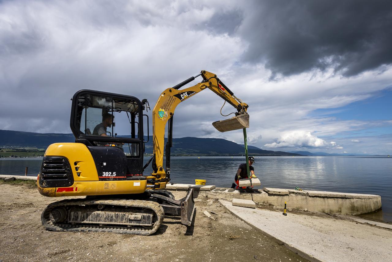 Des ouvriers réparent les margelles de la plage d'Yverdon-les-Bains, abîmées à la suite des intempéries. [KEYSTONE - Jean-Christophe Bott]